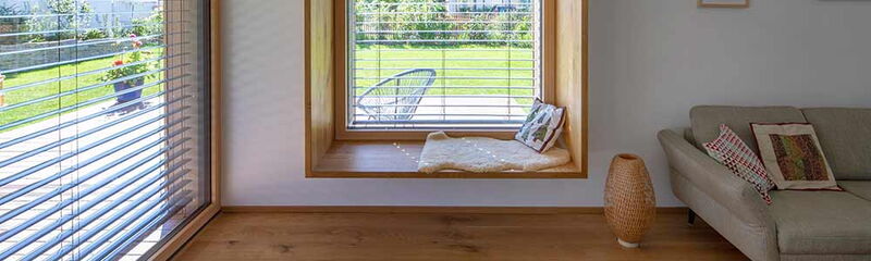 Helle Wohnlandschaft mit Fensterbank, Blick auf den Garten und einem gemütlichen Sofa, das zum Entspannen einlädt.