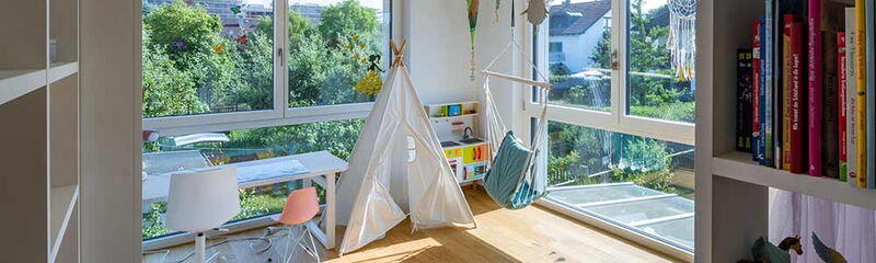 Helle, moderne Kinderzimmeransicht mit Spielzelt, Hängesitz und Blick ins Grüne.