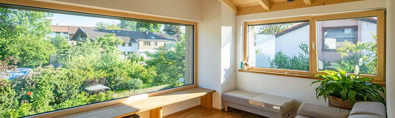Heller Wohnraum mit großen Fenstern und Blick auf einen blühenden Garten