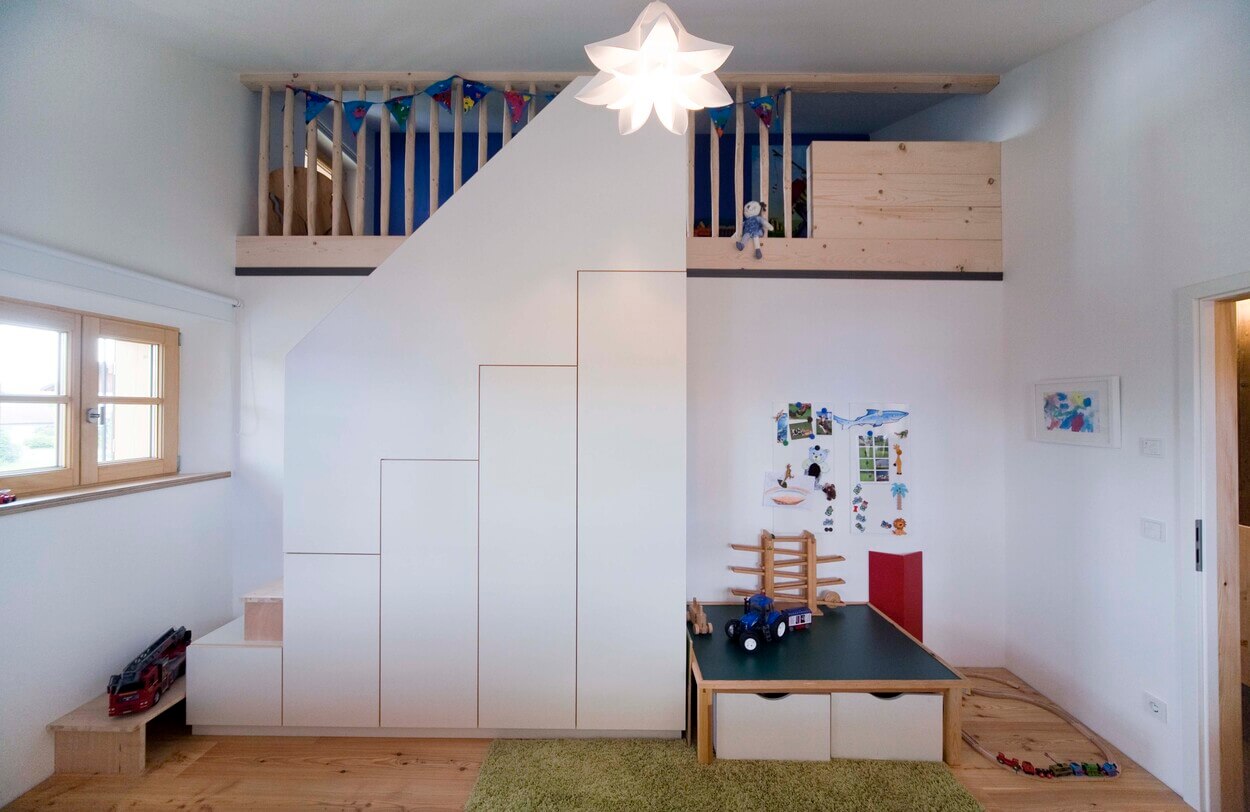 Ein modernes Kinderzimmer im Passivhaus-Stil mit Hochbett, Spielzeug und kreativer Wandgestaltung in Chieming.
