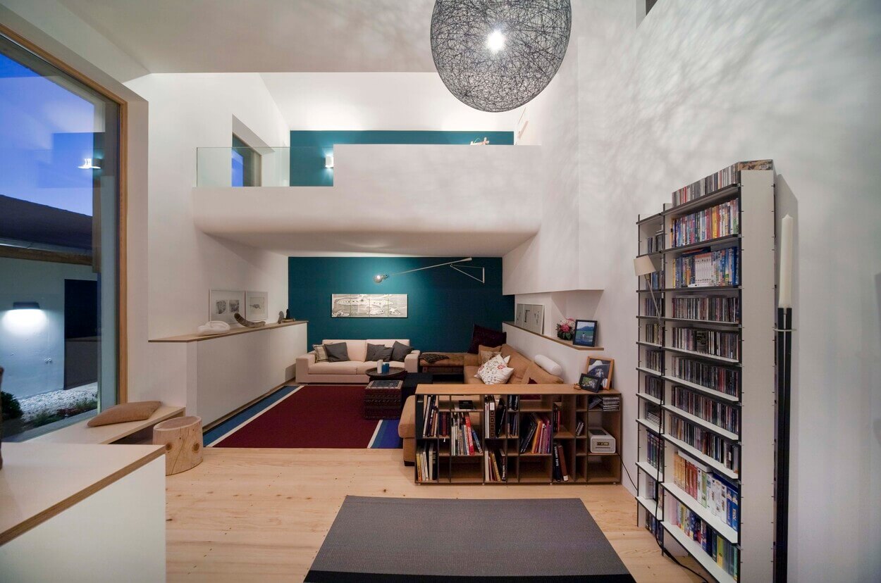 Modernes Wohnzimmer in einem Passivhaus in Chieming mit hohen Decken, großen Fenstern und gemütlicher Leseecke.