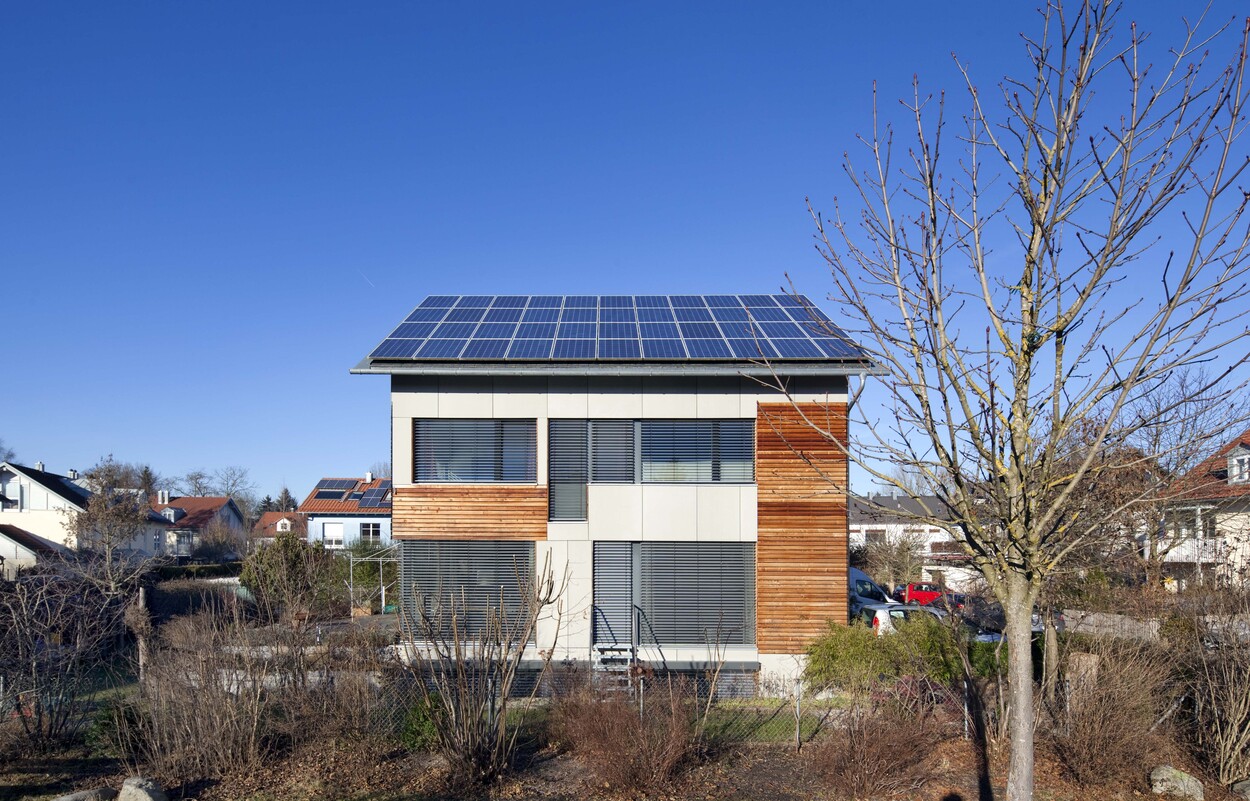 Ein modernes Passivhaus in Fürstenfeldbruck mit Solarpanelen auf dem Dach steht unter klarem, blauem Himmel.