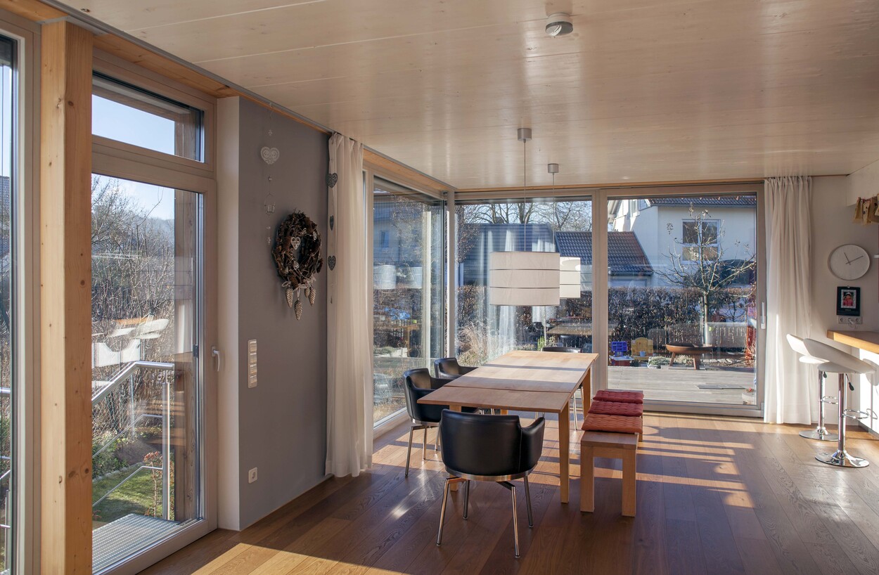 Ein sonnendurchfluteter Essbereich im Passivhaus mit großen Fenstern und Holzboden in Fürstenfeldbruck.