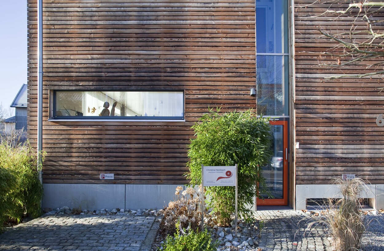 Ein modernes Passivhaus in Fürstenfeldbruck mit Holzfassade und großen Fenstern, umgeben von gepflegtem Grün.