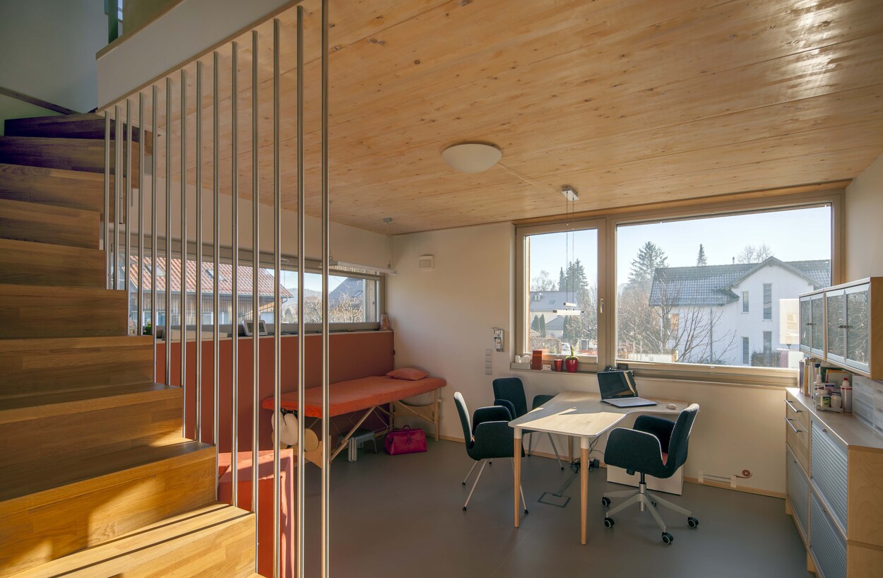 Ein modernes Passivhaus in Fürstenfeldbruck zeigt ein Büro mit Holzboden, viel Tageslicht und einem Ausblick aus großen Fenstern.
