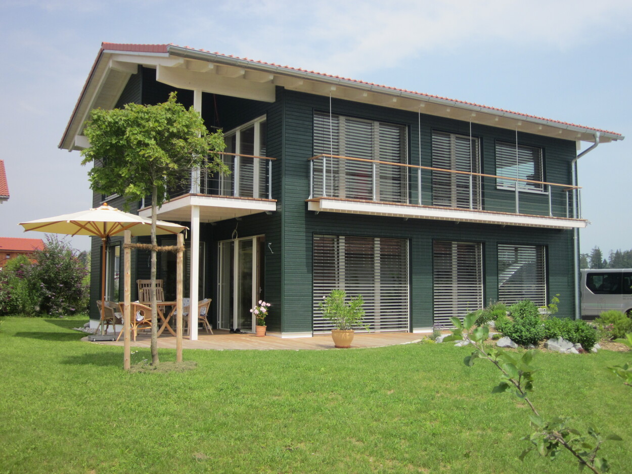 Ein modernes Passivhaus in Breitbrunn mit großen Fenstern und einem gepflegten Garten bei sonnigem Wetter.