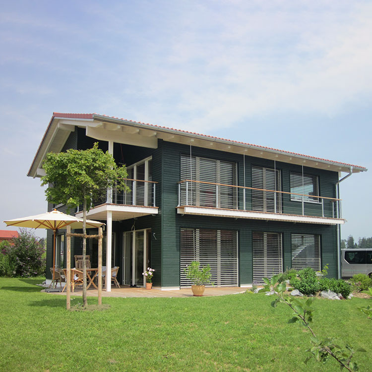 Ein modernes Passivhaus in Breitbrunn mit großen Fenstern und grünem Garten bei sonnigem Wetter.