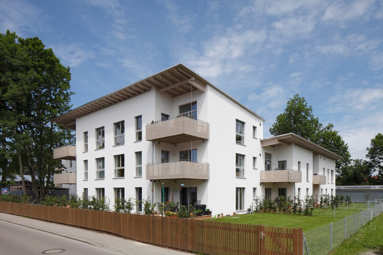 Ein modernes, energieeffizientes Passivhaus mit Balkonen und Garten steht unter sonnigem Himmel im Koribianspark Heufeld.