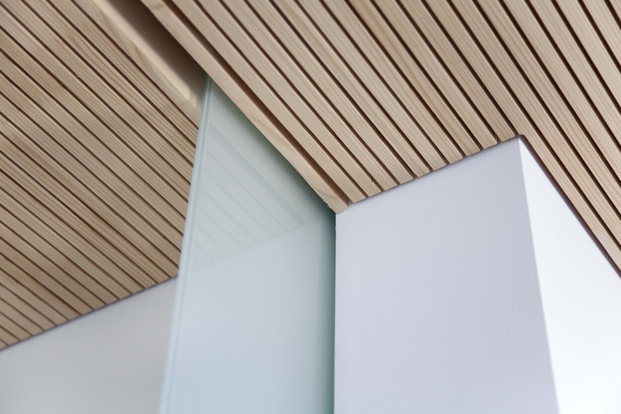 Eine holzverkleidete Decke und eine Glaswand schaffen ein stilvolles Ambiente in einem modernen Passivhaus in Bad Aibling.