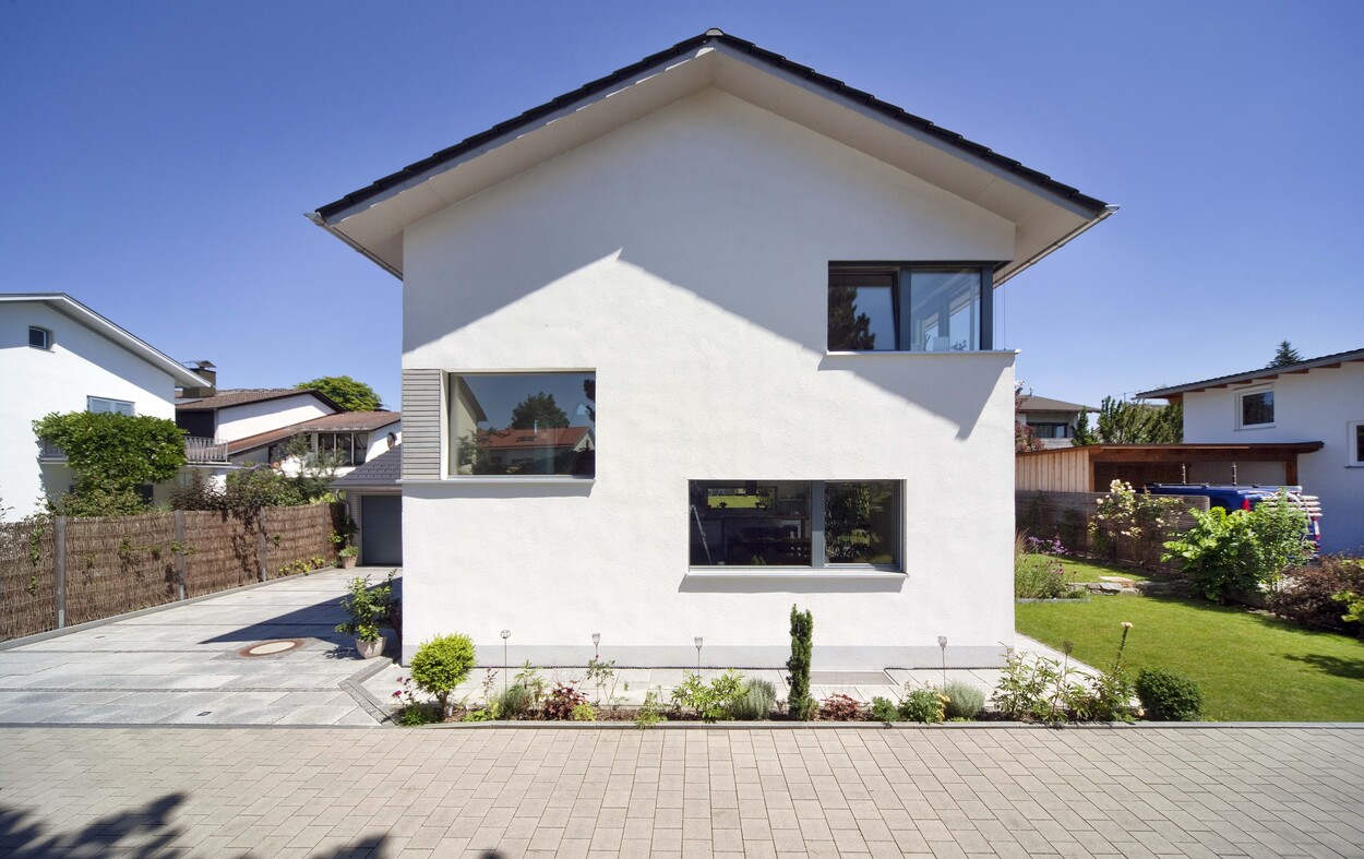 Ein modernes Passivhaus in Bad Aibling steht unter klarem Himmel, umgeben von einem gepflegten Garten.