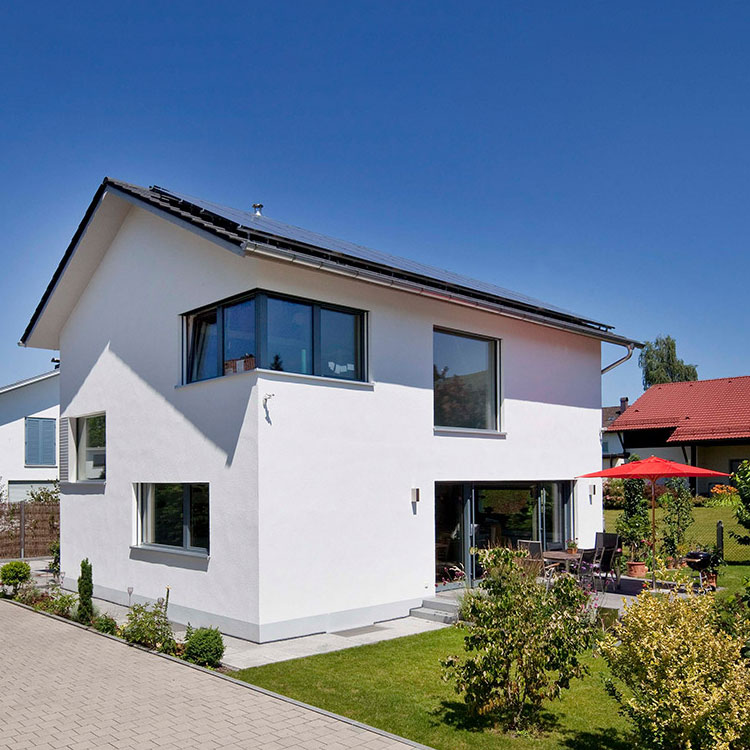 Ein modernes Passivhaus in Bad Aibling strahlt mit weißer Fassade und gepflegtem Garten bei sonnigem Wetter.