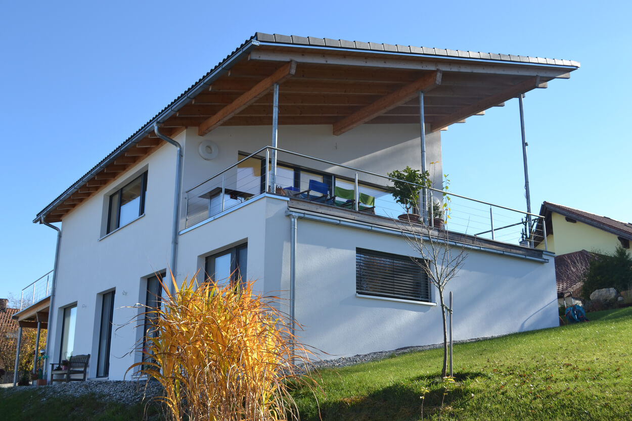 Ein modernes Passivhaus in Soyen mit großer Terrasse und gepflegtem Garten erstrahlt an einem sonnigen Tag.