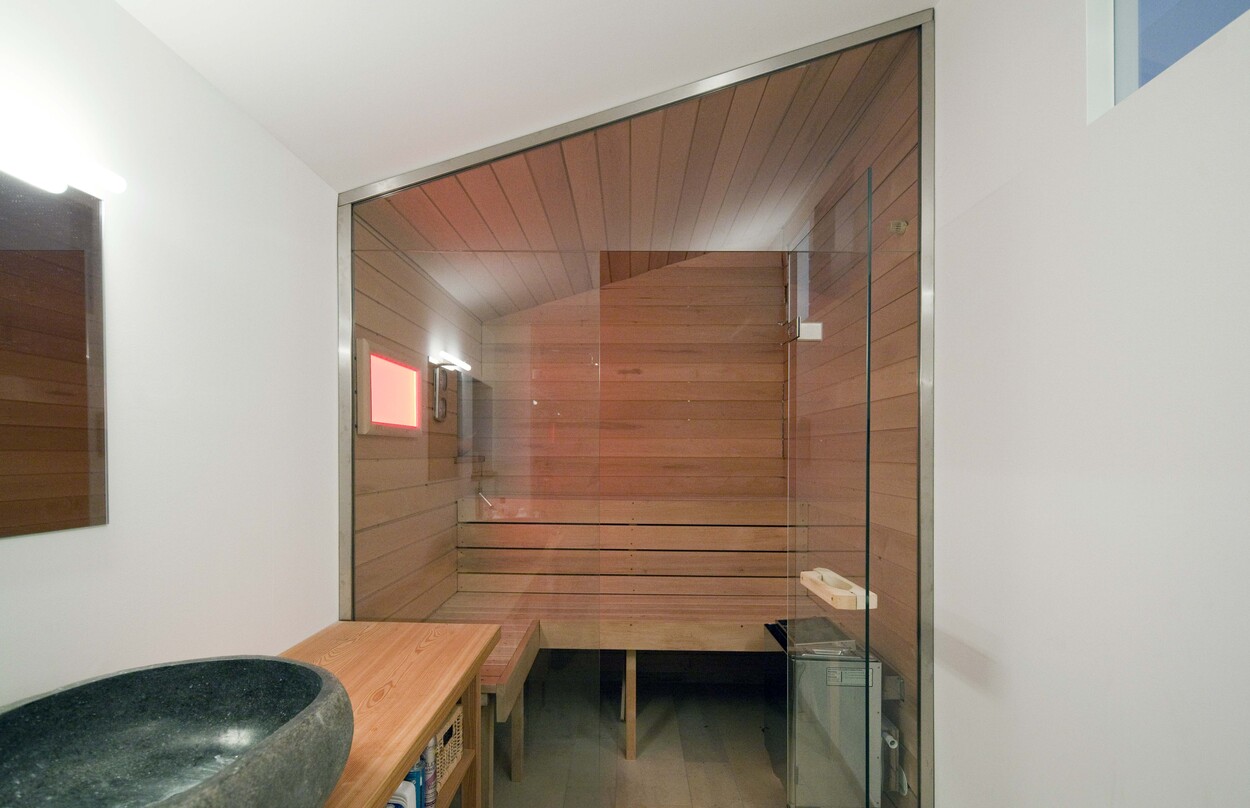 Eine moderne Holzsauna mit Glaswand im Holzhaus in Schliersee bietet eine entspannende Atmosphäre.