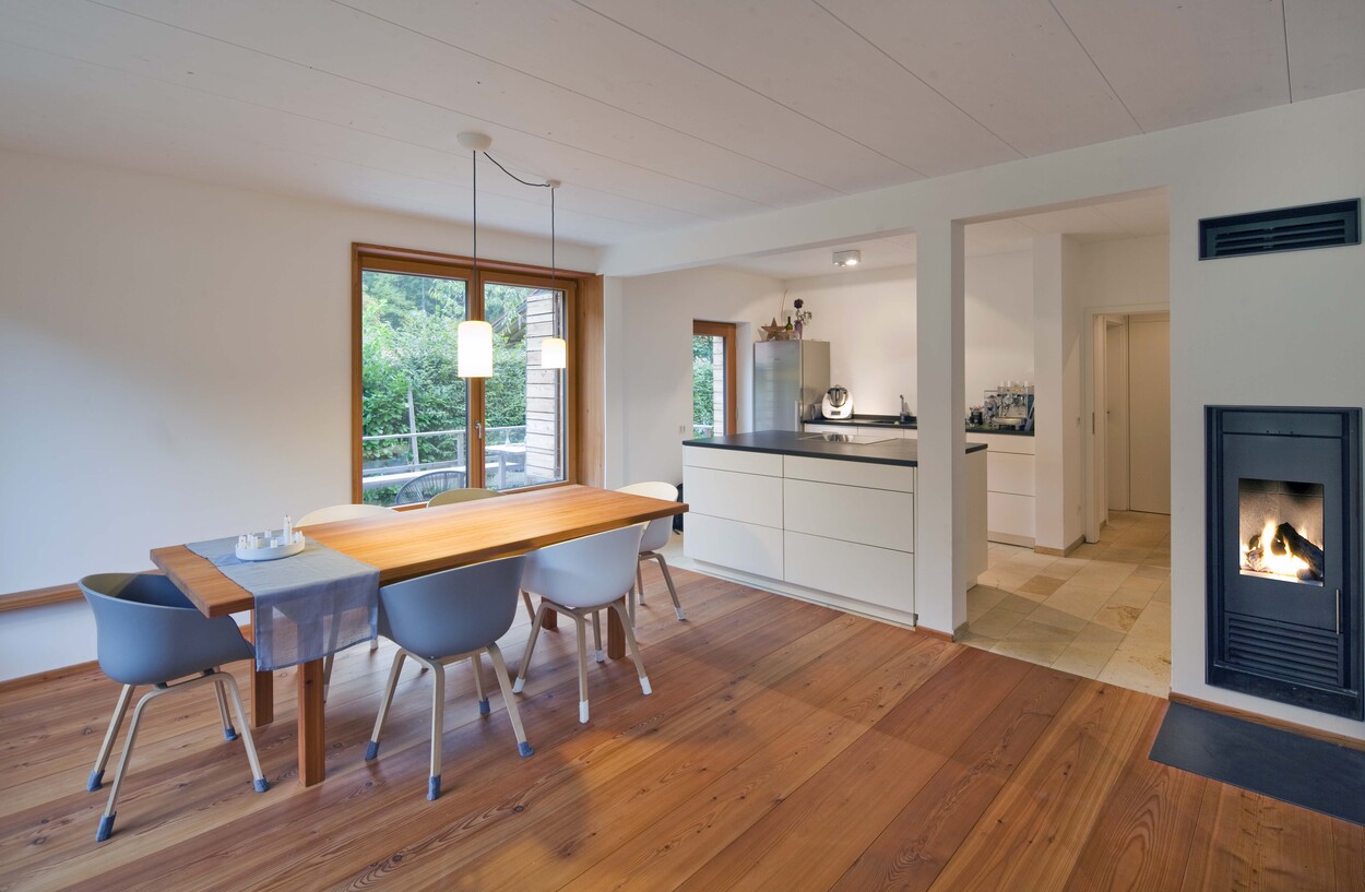 Moderne Küche und Essbereich in einem Holzhaus in Schliersee mit Kamin und Holzboden schaffen eine gemütliche Atmosphäre.