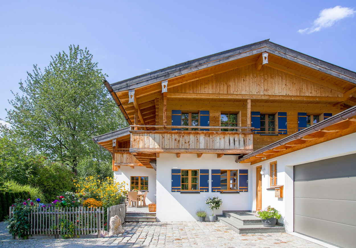 Ein modernes Wohnhaus mit Passivhauskomponenten steht in einem blühenden Garten unter klarem Himmel.
