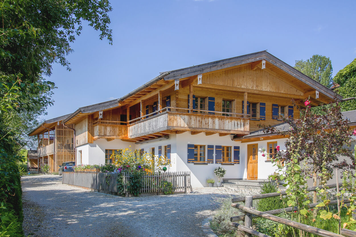 Ein modernes Wohnhaus mit Holzfassade integriert Passivhauskomponenten und ist von einem blühenden Garten umgeben.