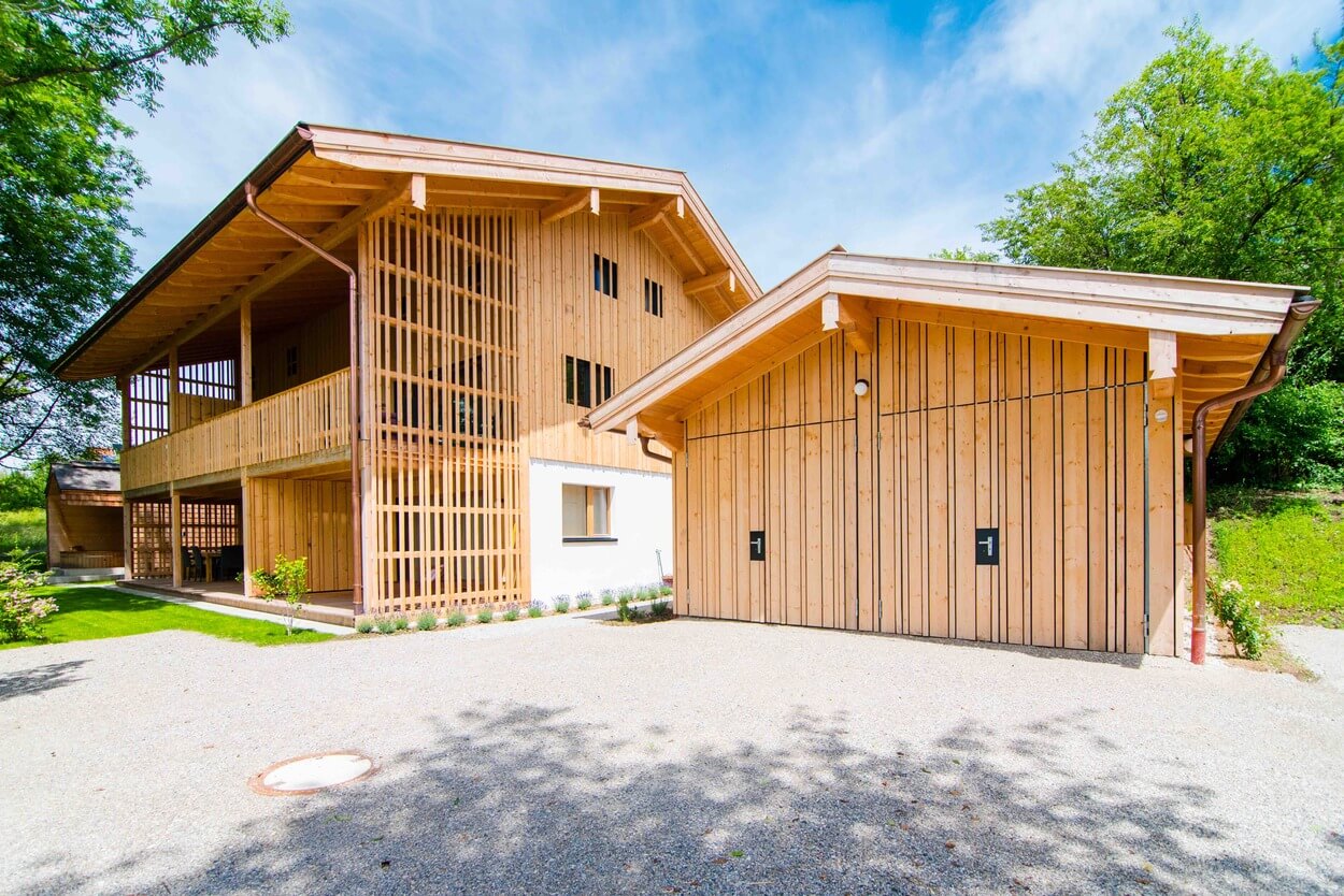 Ein modernes Passivhaus aus Holz erhebt sich unter blauem Himmel in der grünen Umgebung der Wolfsgrube.