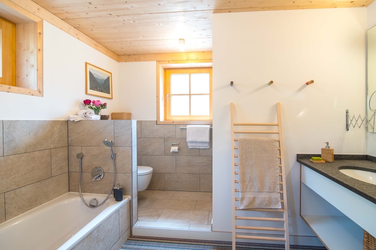 Ein modernes Badezimmer im Passivhaus-Stil zeigt eine Holzdecke, Badewanne, Handtuchhalter und ein stilvolles Waschbecken.