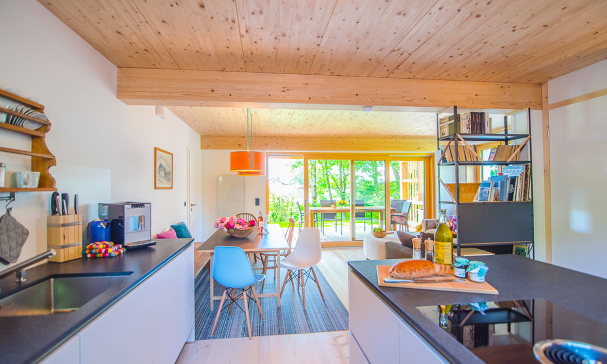 Ein modernes Passivhaus mit Holzbalkendecke und großen Fenstern bietet einen einladenden Blick auf den Garten.