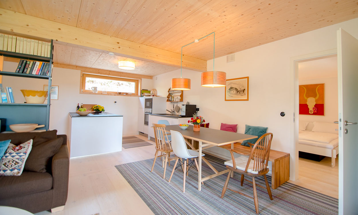 Ein heller Wohnbereich im Passivhaus Wolfsgrube zeigt eine moderne Küche und einen gemütlichen Essbereich mit Holzmöbeln.