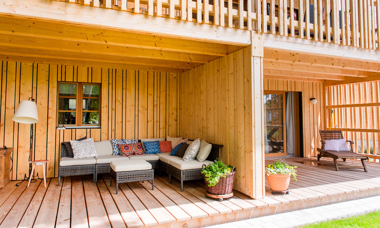 Die Terrasse des Passivhauses in Wolfsgrube zeigt gemütliche Sitzmöbel und Pflanzen auf einem einladenden Holzdeck.