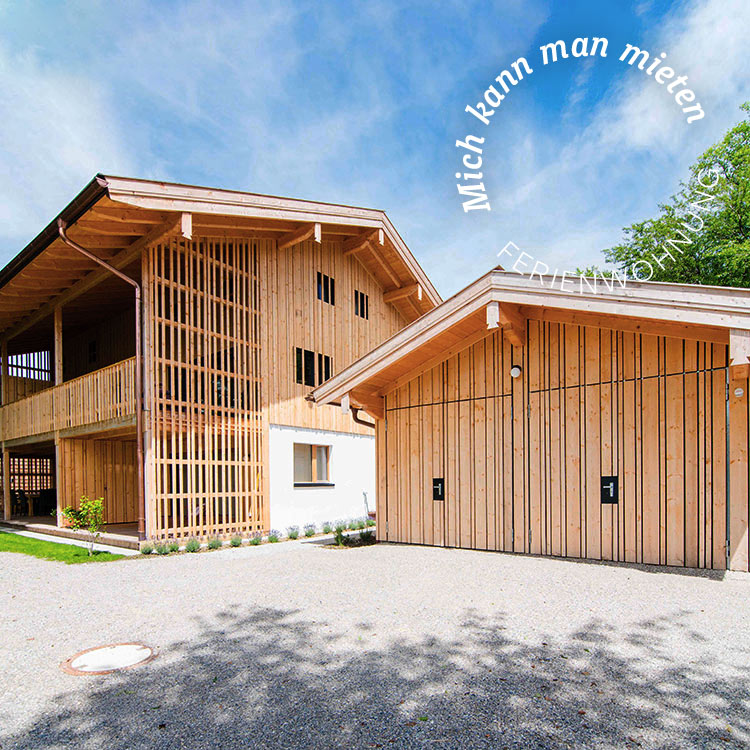 Ein Holzverkleidetes Passivhaus in Wolfsgrube steht unter klarem Himmel, umgeben von grüner Natur.