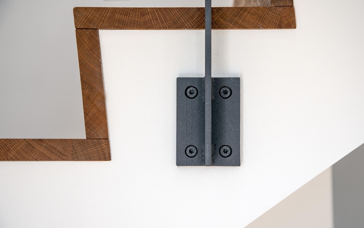 Detailaufnahme einer modernen Treppe in Kirchseeon mit eleganter Holzgeländer und stabiler Metallhalterung.