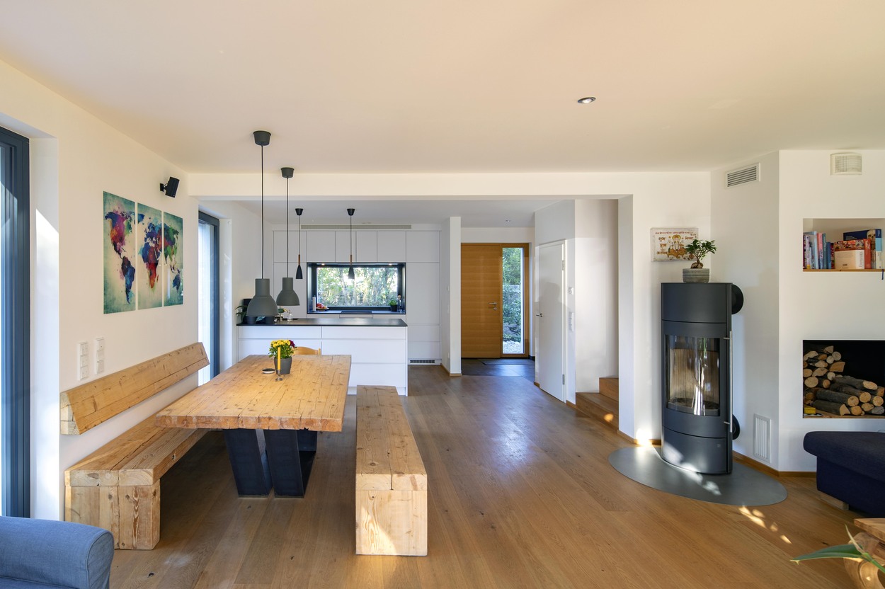 Ein modernes Esszimmer in Kirchseeon mit Holztisch und Kaminofen schafft eine gemütliche Atmosphäre durch stilvolle Wandkunst.