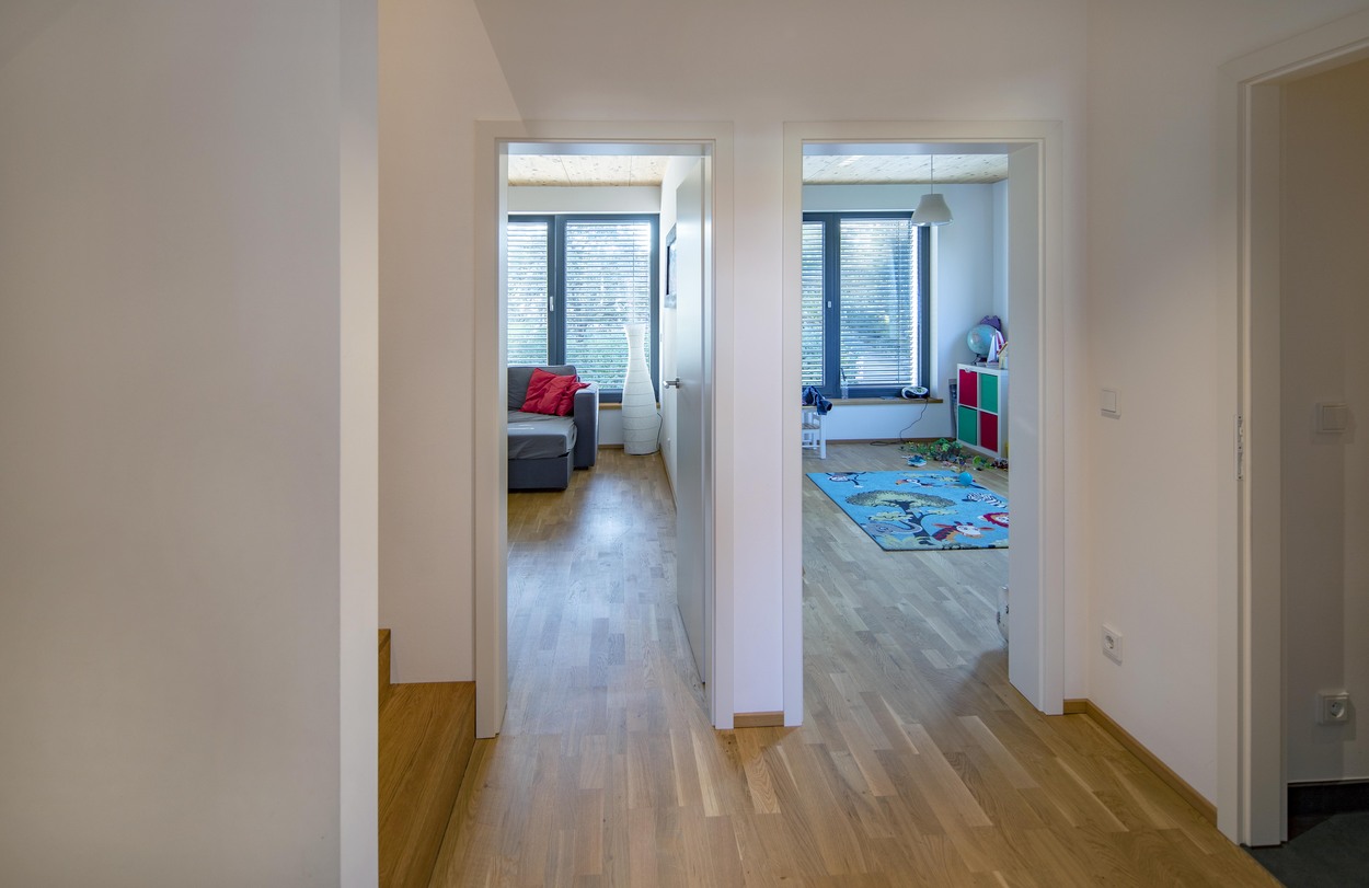 Ein heller Flur in einem Kirchseeoner Mehrfamilienhaus zeigt zwei Zimmer mit Holzfußboden und modernen Möbeln.