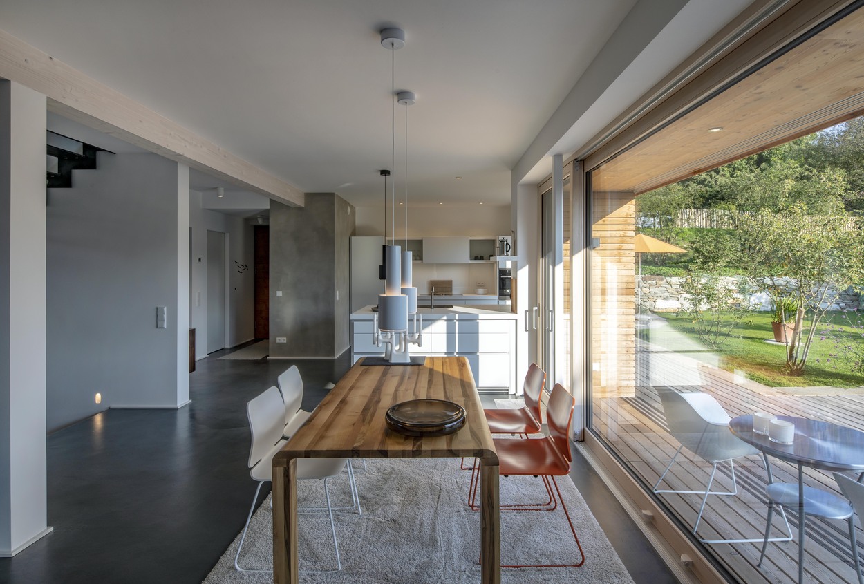 Heller Essbereich eines modernen Holzhauses in Marquartstein mit Blick auf den grünen Garten im Chiemgau.