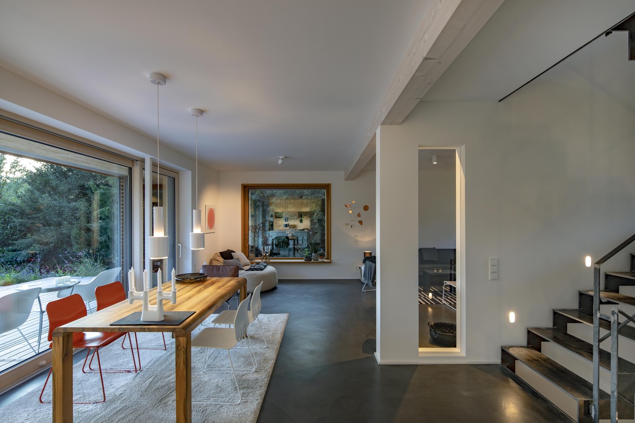 Modernes Wohnzimmer in einem Holzhaus in Marquartstein mit großem Fenster, eleganten Möbeln und Blick auf den Chiemgau.