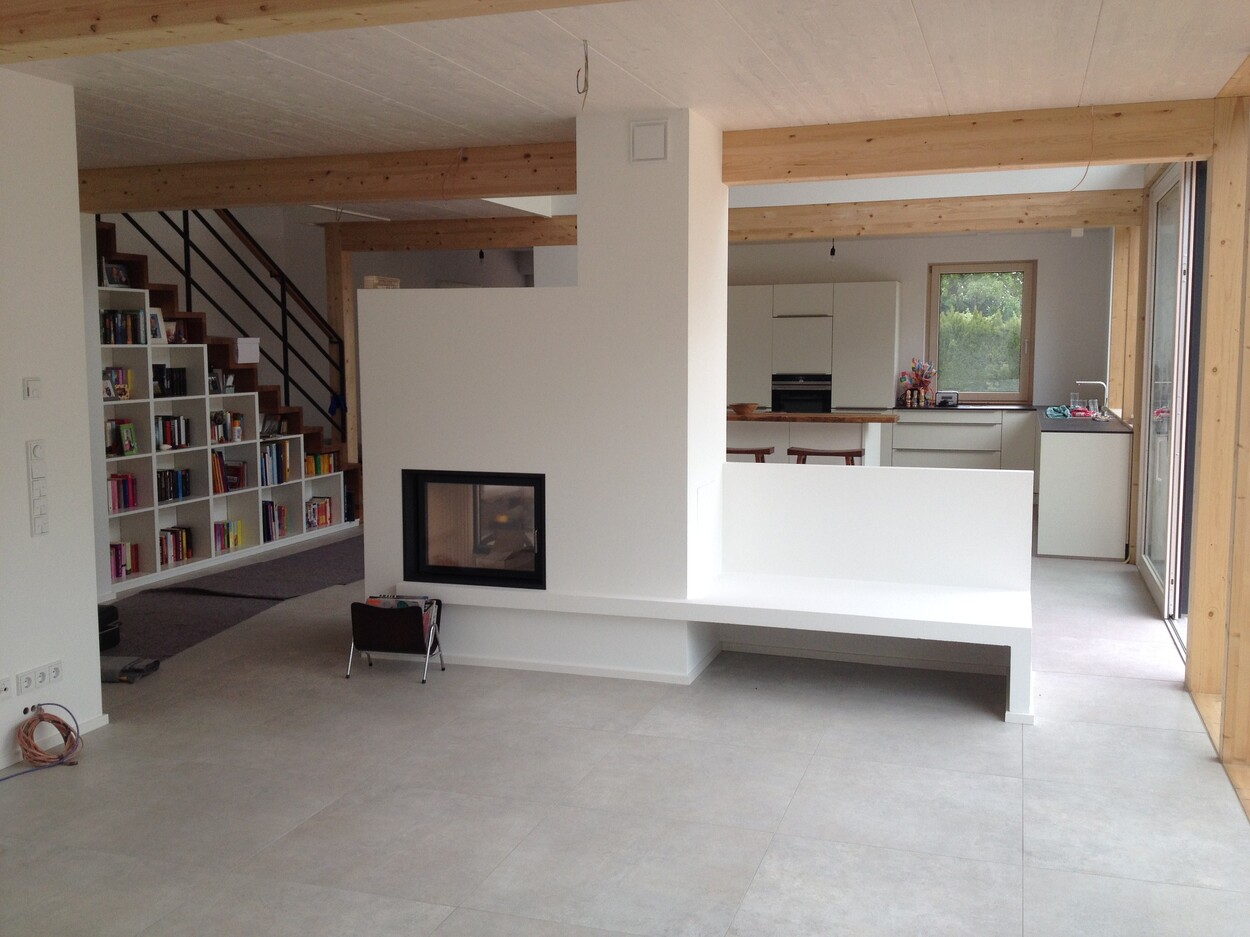 Moderne Innenansicht eines Holzbau-Einfamilienhauses in Feldkirchen mit offener Küche und gemütlichem Kamin.