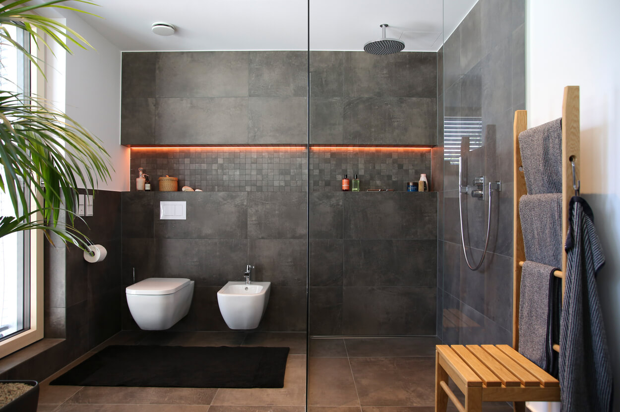 Modernes Badezimmer in einem Münchner Passivhaus mit grauen Fliesen, Regendusche und eleganten Holzdetails.