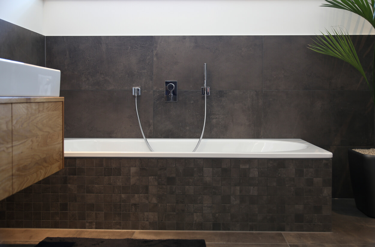 Eine moderne Badewanne ist elegant in dunkle Fliesen eines Münchner Passivhauses integriert.