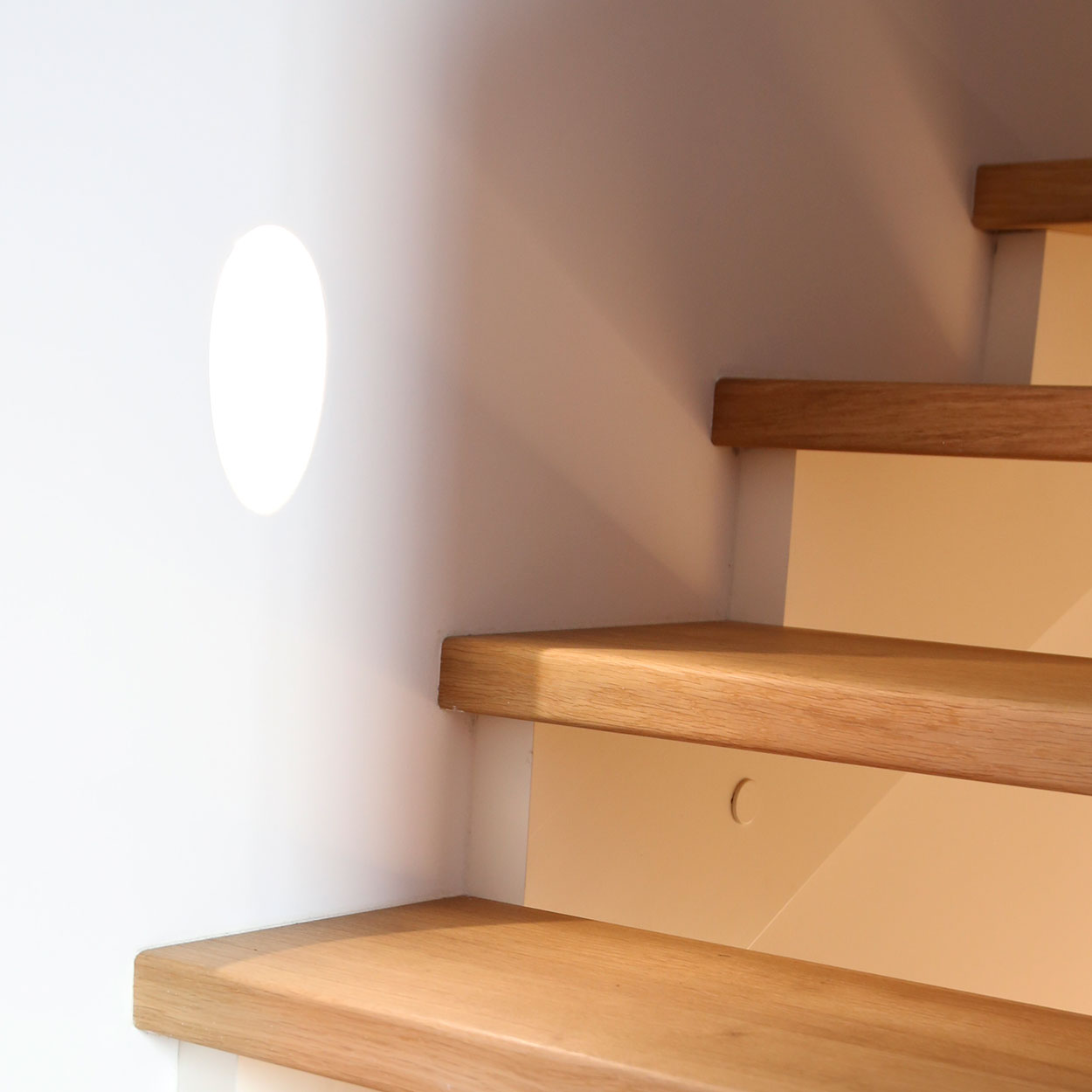 Sonnenlicht fällt auf eine Holztreppe in einem modernen Passivhaus-Doppelhaus in München und erzeugt ein warmes Ambiente.