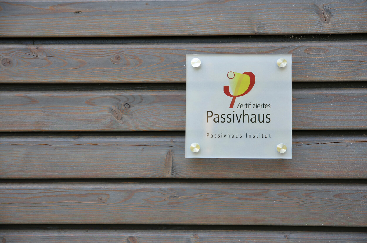 Ein Schild des Passivhaus Instituts ist an der Holzfassade eines Doppelhauses in München befestigt.