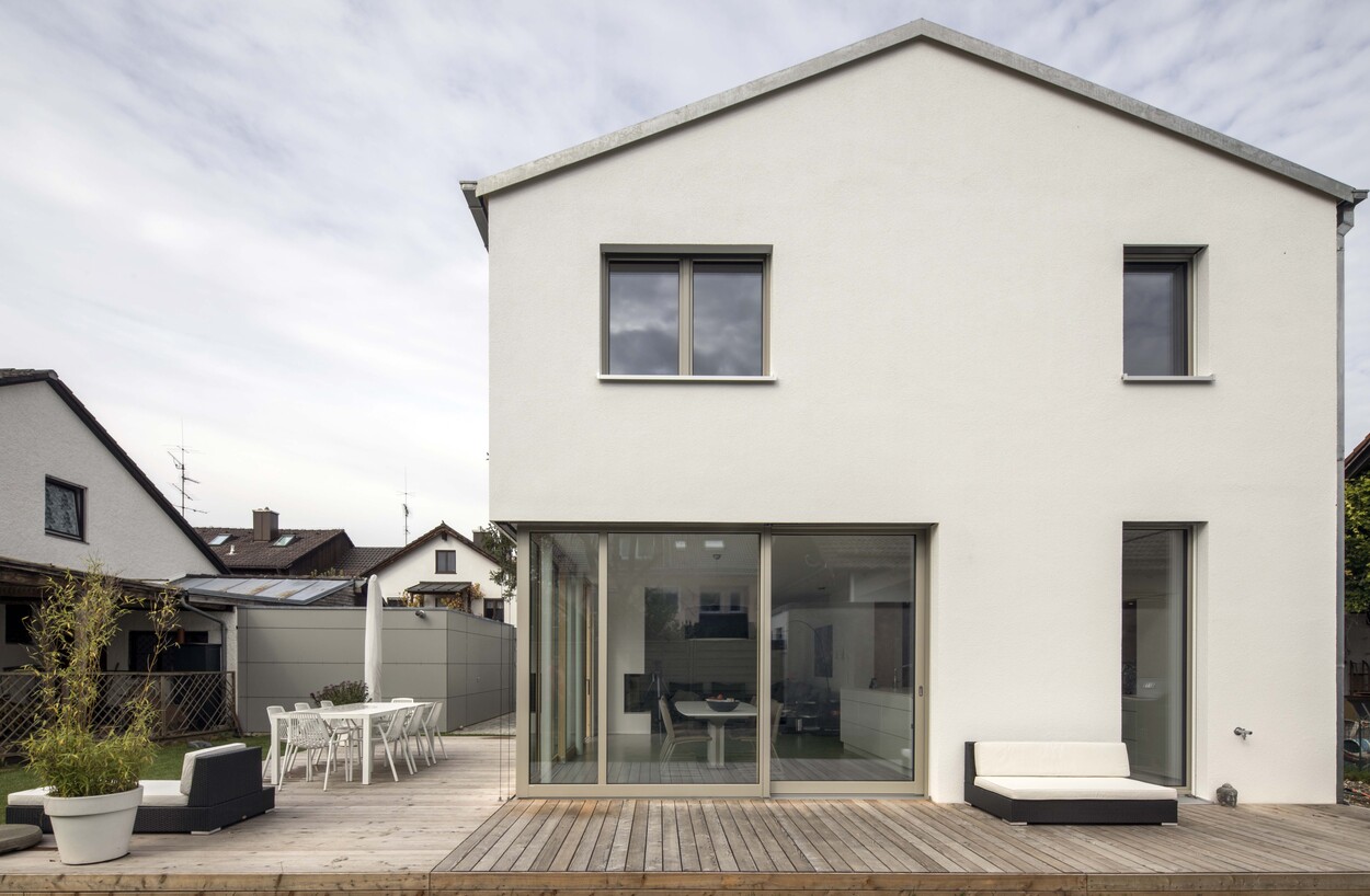 Ein modernes Energiesparhaus aus Holz in Putzbrunn zeigt seine große Terrasse und den schlichten, weißen Außenputz.