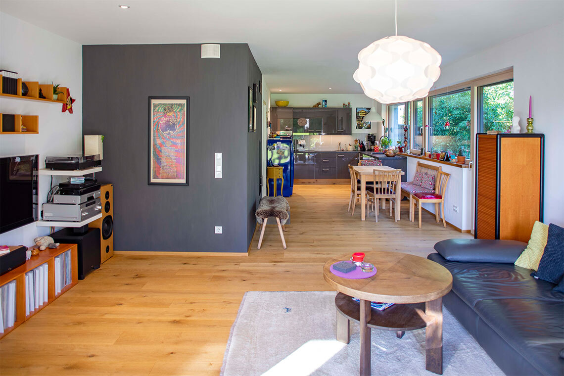 Helles Wohnzimmer in einem Passivhaus in Bad Aibling mit modernem Interieur, großen Fenstern und offener Küche.