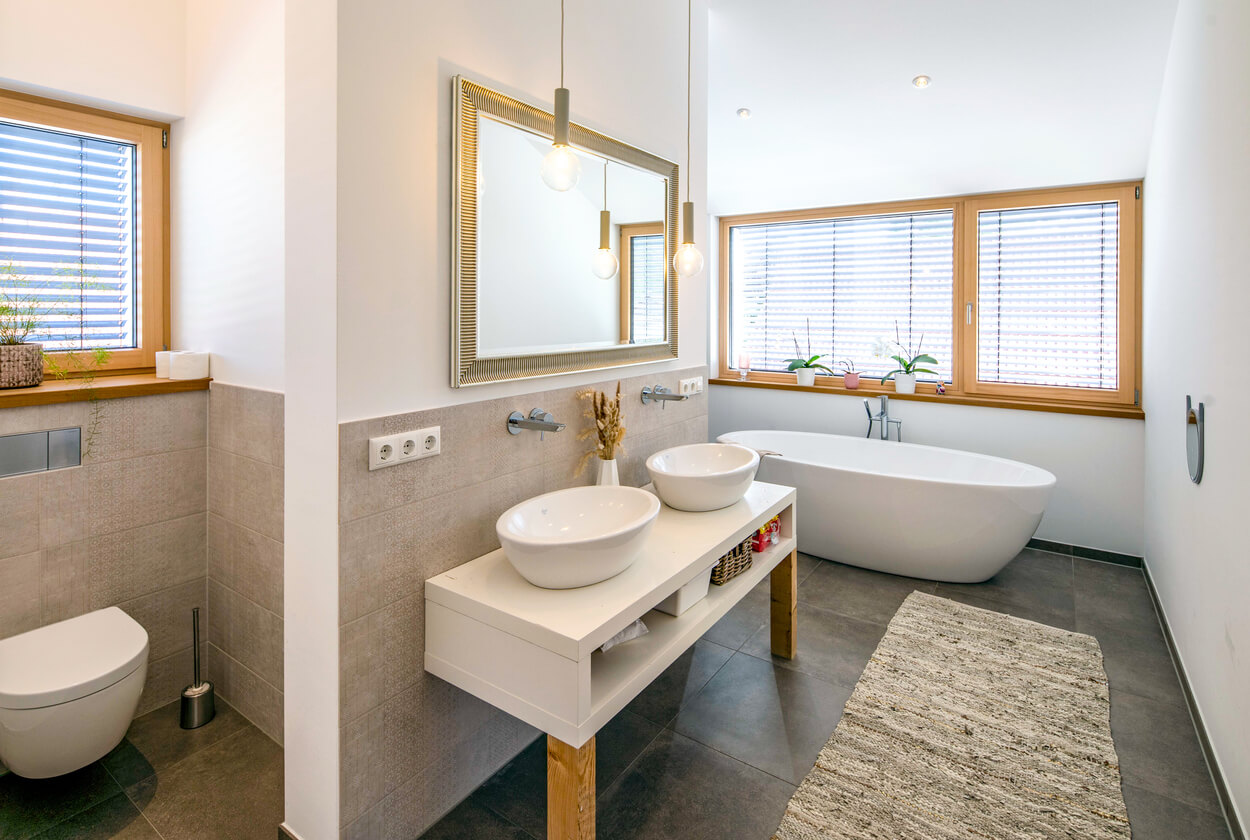 Ein modernes Badezimmer in Fahrenzhausen mit freistehender Badewanne, Doppelwaschbecken und großen Fenstern für viel Tageslicht.
