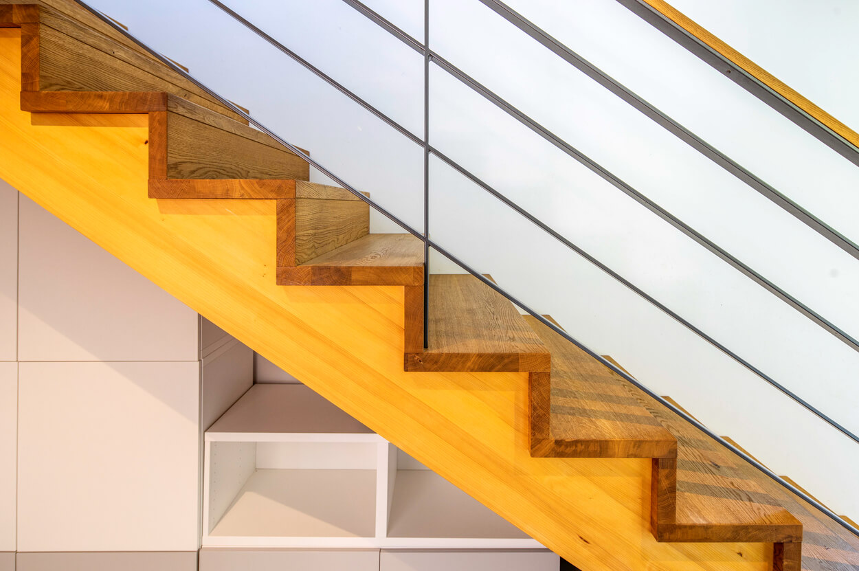 Detailansicht einer modernen Holztreppe im Passivhaus Fahrenzhausen mit klaren Linien und integrierten Stauräumen.