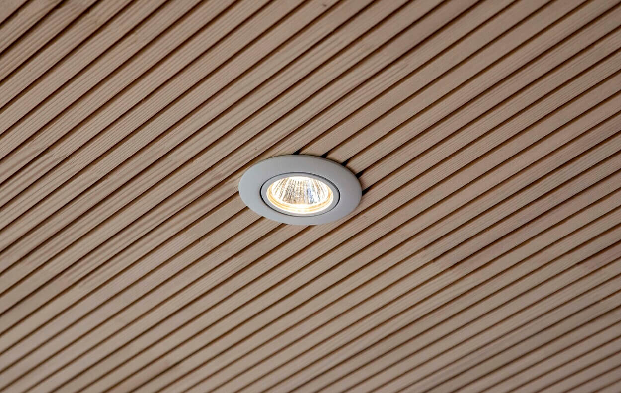 Eine moderne Holzdecke mit eingebautem LED-Spot beleuchtet ein Passivhaus in Eichenau.