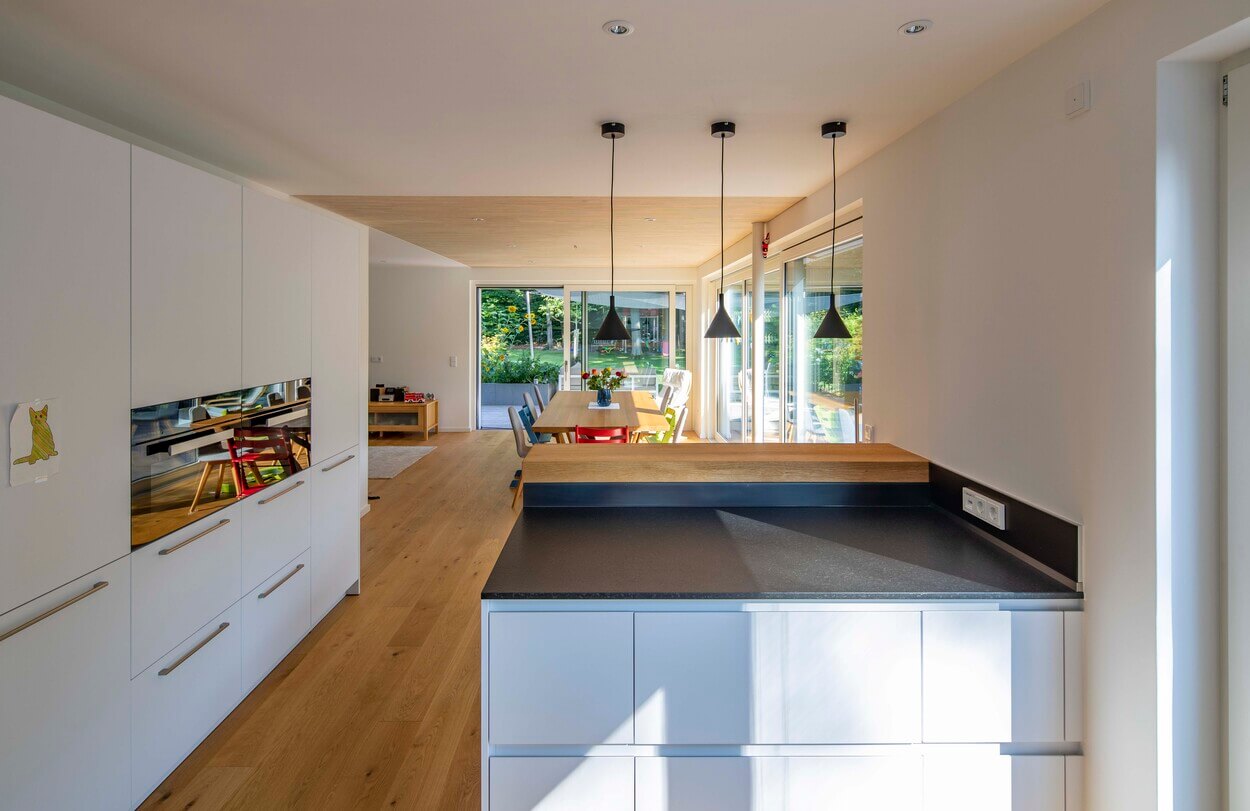 Der helle Wohnbereich in Eichenau zeigt moderne Küchenmöbel und einen Esstisch mit stilvollen Hängelampen.