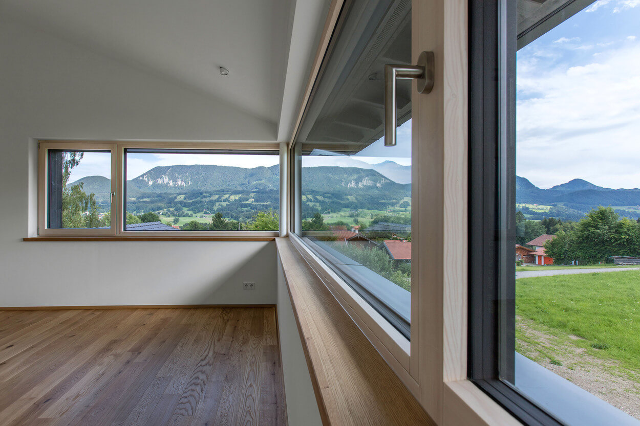 Ein modernes Zimmer mit Holzboden bietet durch große Fenster einen beeindruckenden Blick auf die Berge bei Samerberg.