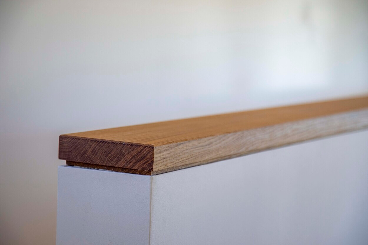 Detailaufnahme eines hölzernen Handlaufs in einem modernen Holzhaus in Otterfing zeigt die feine Maserung des Holzes.