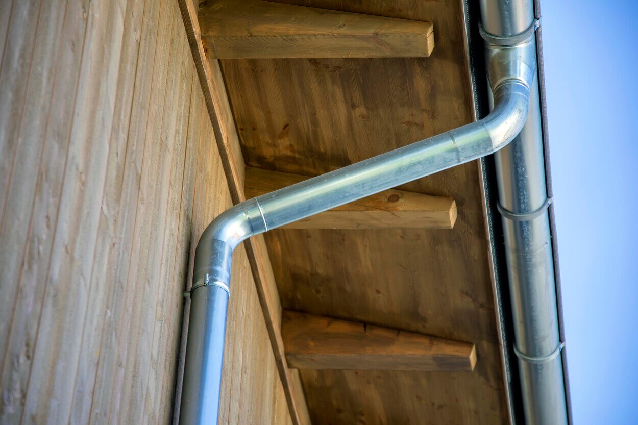 Eine silberne Regenrinne verläuft elegant entlang des Holzdachs eines Gebäudes in Otterfing.