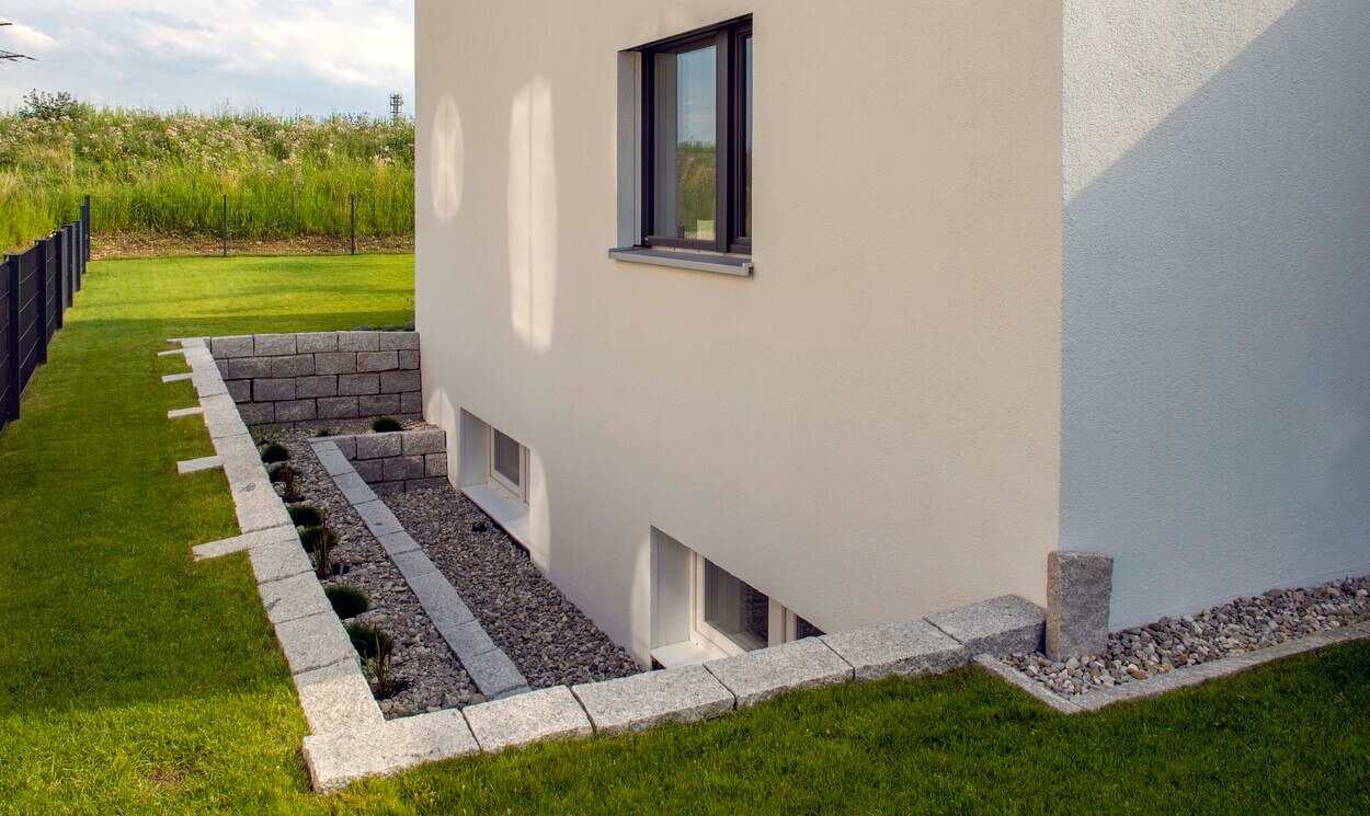 Ein modernes Passivhaus in Pliening zeigt elegante Linien aus Steinplatten, umgeben von einem gepflegten Garten.
