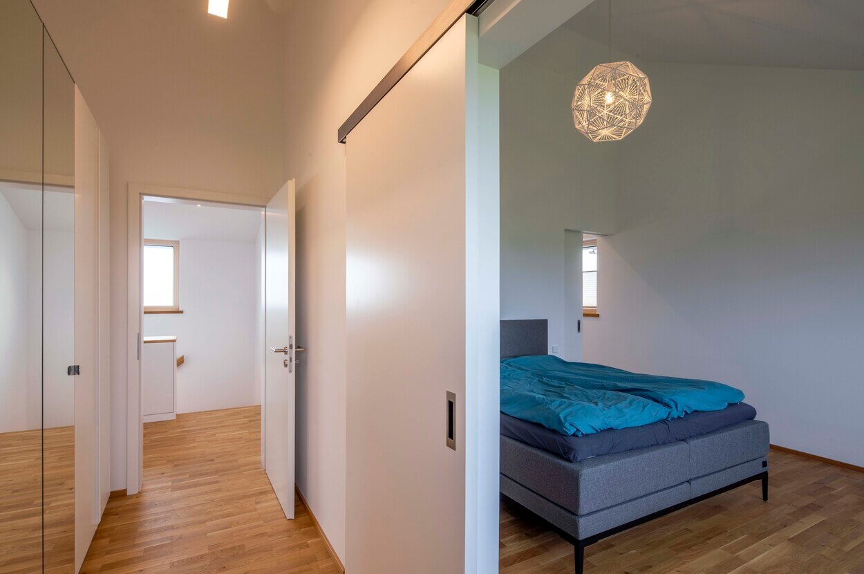 Ein modernes Schlafzimmer mit Holzboden im Passivhaus-Stil wird von natürlichem Licht durchflutet.