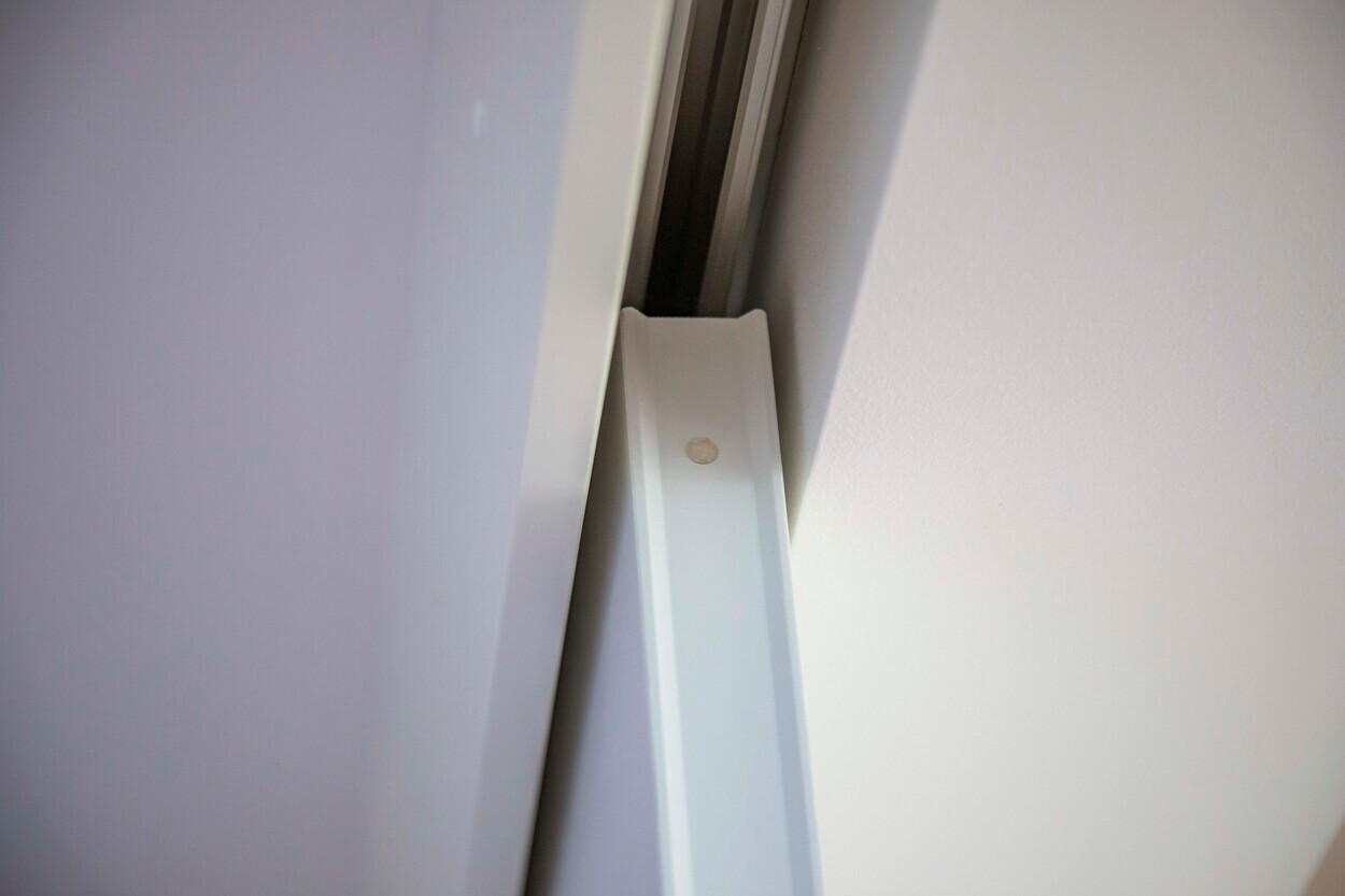 Eine weiße Schiebetür in einem Holzhaus in Dachau zeigt die detaillierte obere Führungsschiene.