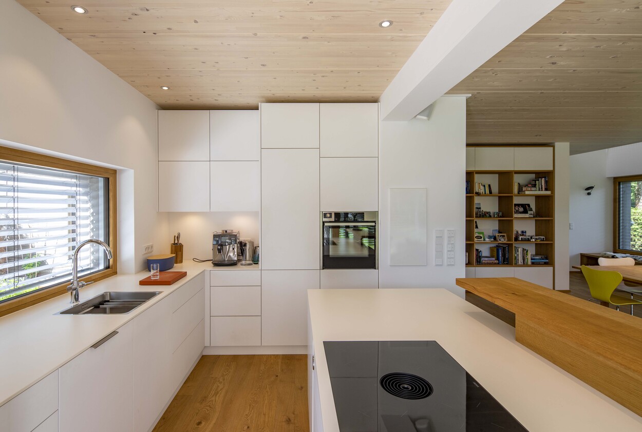 Moderne, helle Küche in Gröbenzell mit weißen Schränken, Holzboden und großem Fenster für natürlichen Lichteinfall.