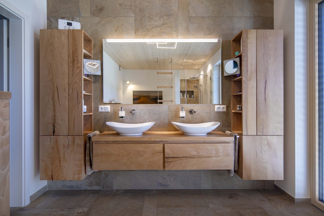 Ein modernes Badezimmer in einem Einfamilienhaus bei Prien mit zwei eleganten Waschbecken und stilvollen Holzschränken.